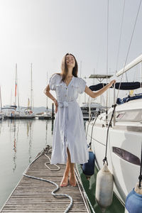 Happy young woman standing by boat on jetty