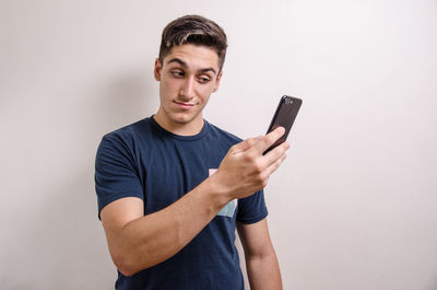 Young man using smart phone against white background