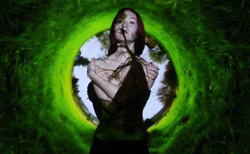 Portrait of topless woman standing in front of projection screen