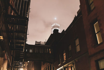 Low angle view of illuminated buildings in town against sky at night