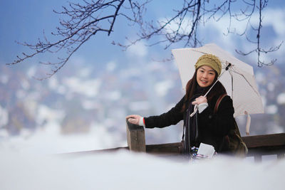 Woman sitting on snow covered tree