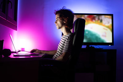 Side view of man using mobile phone while sitting on table