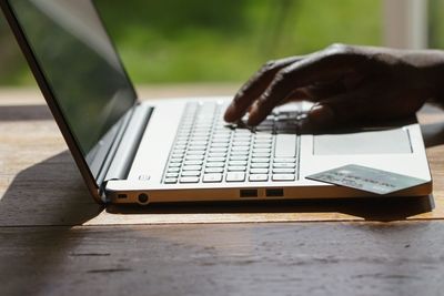 Cropped hands of man using laptop on table