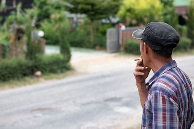 Senior man smoking cigarette while standing on road