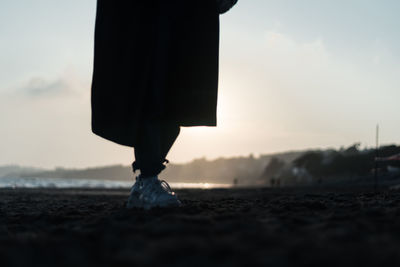 Low section of man standing on land at sunset