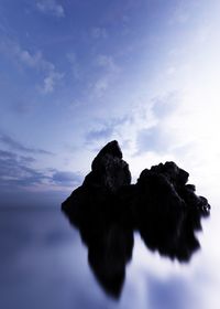 Rock formations in sea against blue sky