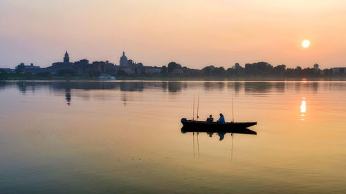 Silhouette boat in lake against sky during sunset