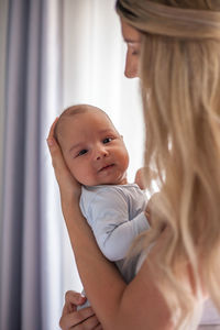 Close-up of smiling mother with cute baby at home