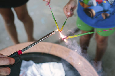 Children holding sparklers being burned by father with lighter