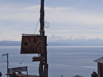 Information sign by sea against sky during winter