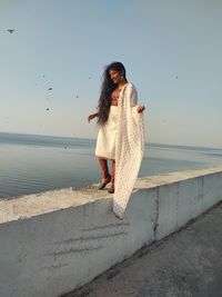 Woman standing on beach against sky