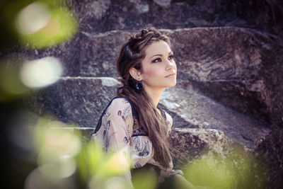 Young woman looking away against rocks