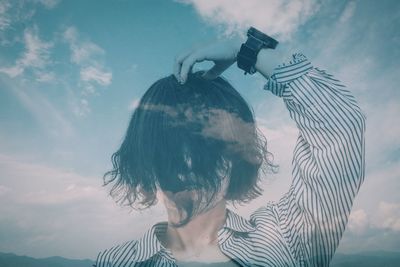 Portrait of woman photographing against sky