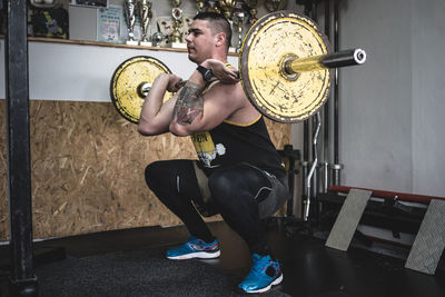 Young man lifting barbell in gym