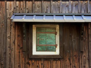 Tiny copper plated window with rusty hinges in an old japanese building