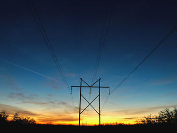 Low angle view of electricity pylon against sky during sunset