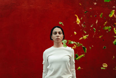 Portrait of young woman against red wall