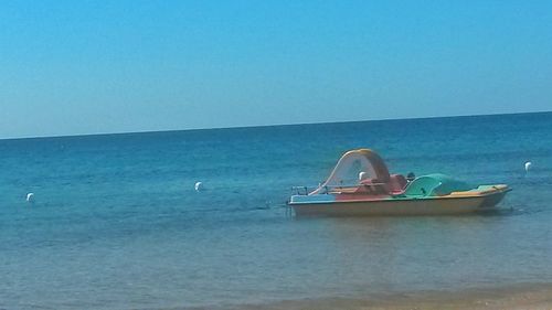 Boat in sea against clear blue sky