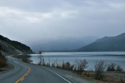 Road by mountains against sky