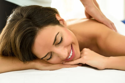 Cropped hand of masseuse giving massage to young woman