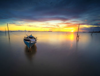 Boat moored in sea against sky during sunset