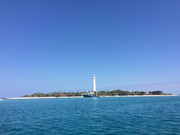 Lighthouse sailing on sea against clear blue sky