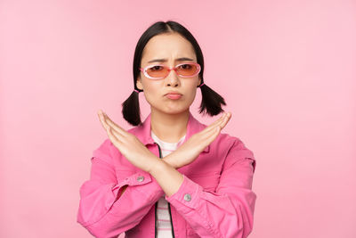 Portrait of young woman against pink background