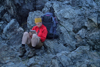 High angle view of hiker using digital tablet on rocky mountain