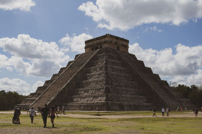 Tourists at historical building against cloudy sky