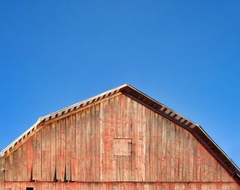 Low angle view of old red building against clear blue sky