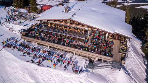 Aerial drone video of crowded ski restaurant with terrace full of people. apres ski bar surrounded 