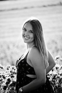 Portrait of smiling young woman standing on field