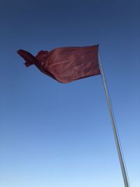 Low angle view of flag against clear blue sky