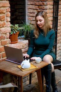 Woman using laptop while sitting at sidewalk cafe