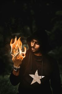 Digital composite image of man with burning hand at night