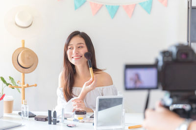 Portrait of young woman using phone on table