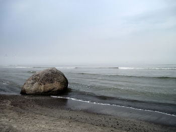 Surface level of calm beach against the sky