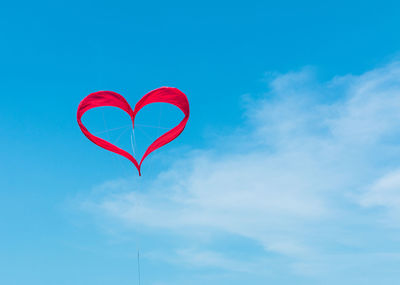 Low angle view of red heart shape kite against sky