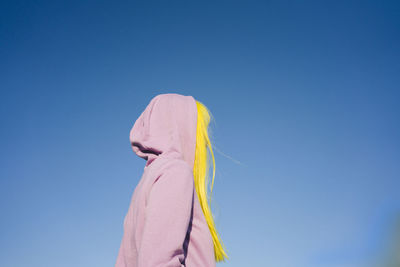 Low angle view of woman against blue sky