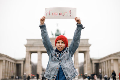 Low angle view of woman with arms raised standing against wall