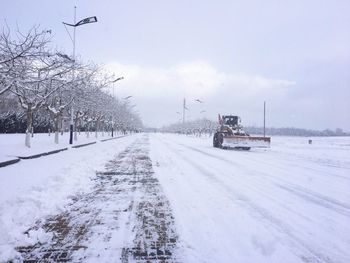 Tire tracks on snow covered road against sky