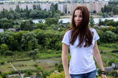 Portrait of young woman standing against trees