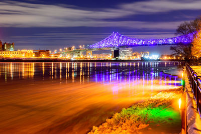 Illuminated bridge over river at night