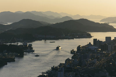 View of buildings in city at waterfront during sunset