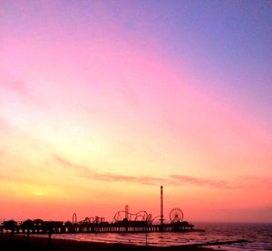 Silhouette pier over sea against romantic sky at sunset