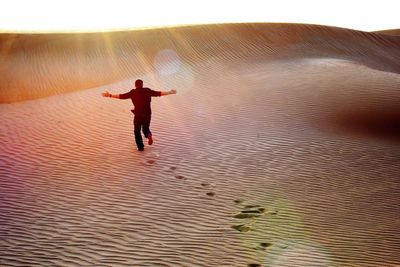 Rear view of man walking on desert