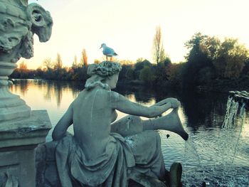 Statue by lake against clear sky