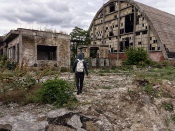 Rear view of a man walking on abandoned house