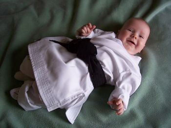 High angle view of child with black belt lying down on green blanket