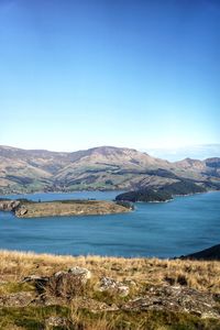 Scenic view of lake and mountains against clear blue sky